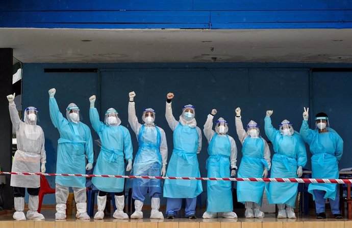 Trabajadores saniarios saludan antes de comenzar su turno en un centro de test de coronavirus en Kampung Gersik, en Malasia