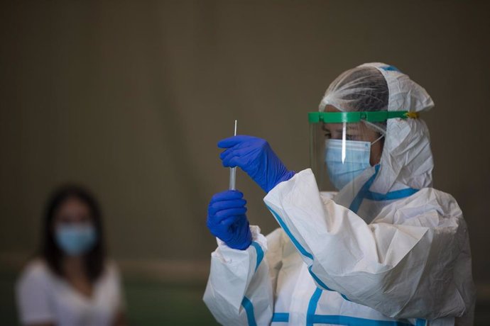 Una sanitaria atiende a una mujer durante las pruebas de cribado de covid-19 con test de antígenos en pabellones deportivos de Sevilla