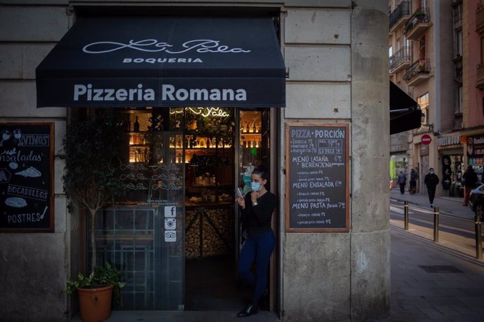 Una trabajadora observa las inmediaciones de su establecimiento de Barcelona, Catalunya (España), tras la paralización de la actividad durante dos semanas en bares restaurantes, el 16 de octubre del 2020.