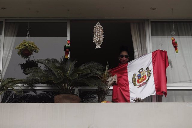 Una vecina del distrito limeño de Surquillo alienta a sus vecinos desde el balcón de su casa con una bandera de Perú.