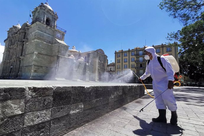 31 August 2020, Mexico, Oaxaca: Aworker wearing a protective suit disinfects th