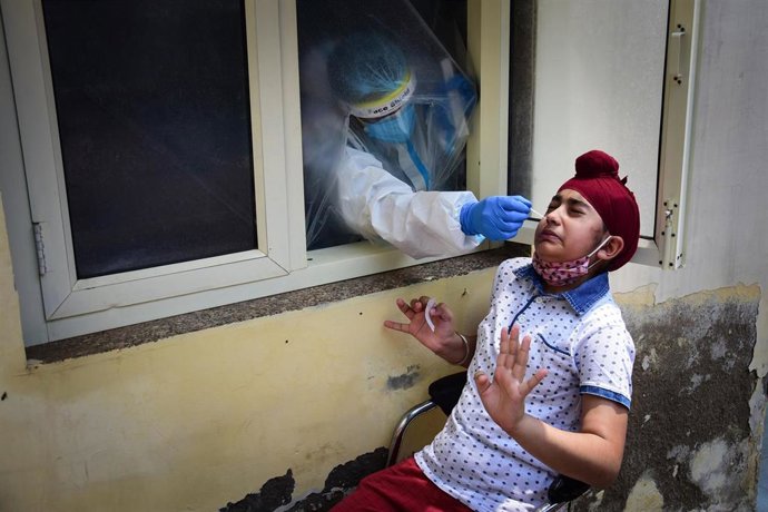 Un médico toma muestras a un paciente para un test de coronavirus en Nueva Delhi