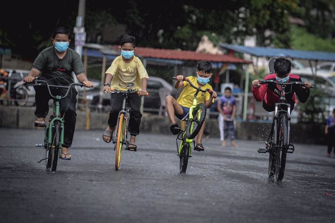 Niños con mascarilla montando en bicicleta en la localidad malasia de George Tow