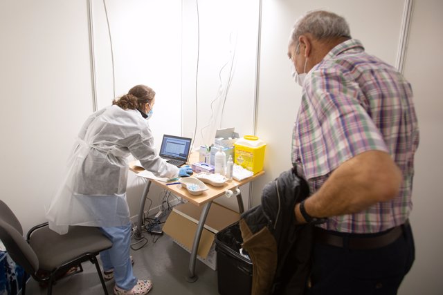 Una enfermera atiende a un paciente antes de ponerle la vacuna contra la gripe en el recinto habilitado en el Iradier Arena, en Vitoria, Álava