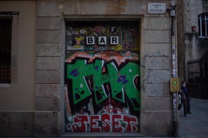 Un graffiti en la puerta cerrada de un bar en el centro de Barcelona en la primera mañana después del toque de queda en la ciudad, en Barcelona, Catalunya (España), a 26 de octubre de 2020. Catalunya ha aplicado desde este domingo a las 22 horas hasta e