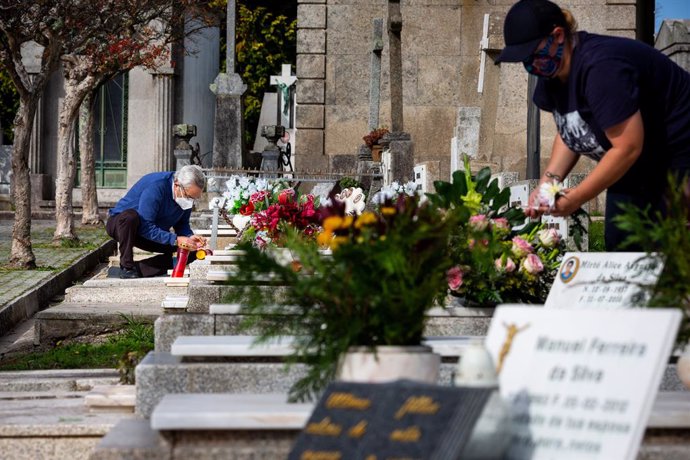 28 October 2020, Portugal, Porto: People wearing face masks are seen cleaning the graves at Agramonte cemetery before the National Day of All Saints. People are still allowed to visit the cemetery before the National Day of All Saints to pay tribute to 