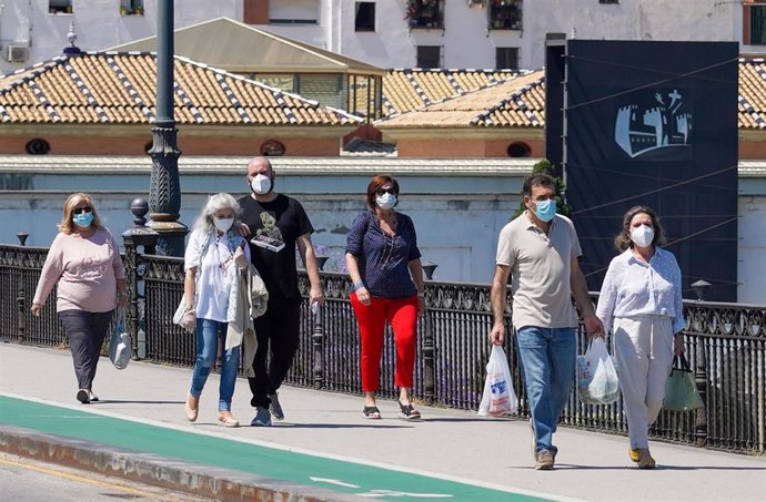 Ciudadanos paseando por el puente de triana  en el  primer día del uso obligatorio de mascarillas por el Covid-19. Sevilla a 21 de mayo del 2020