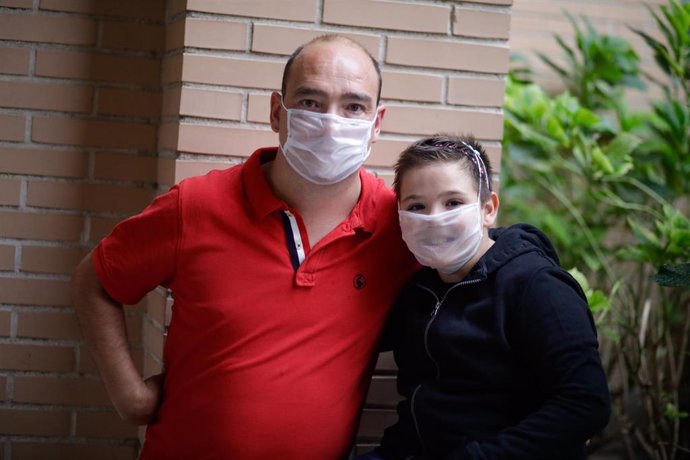 Álvaro Romero (d), con una pérdida del 50% en un oído y usuario de un implante de conducción, junto a su padre Francisco Javier Romero, posan a la cámara con una mascarilla transparente certificada -pero no homologada por el Ministerio de Sanidad