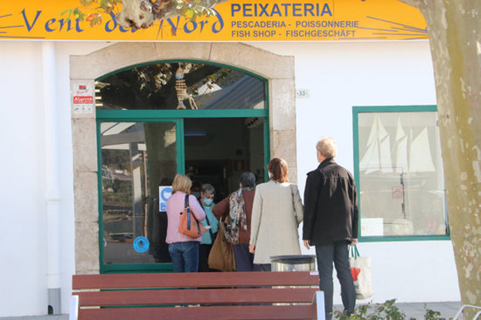 Unes persones fent cua per comprar a la peixateria del Port de la Selva aquest 30 d'octubre del 2020. (Horitzontal)
