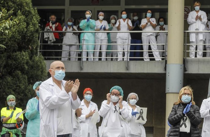 Sanitarios protegidos con mascarillas aplauden conmocionados tras el minuto de silencio en la entrada del Hospital Doctor Peset por la técnica de enfermería fallecida por coronavirus, en Valencia/Comunidad Valenciana (España) a 6 de abril de 2020.