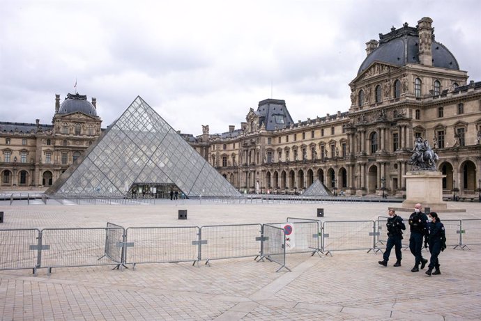 30 October 2020, France, Paris: Police officers walk in front of the closed Louvre museum, as France goes into coronavirus lockdown for the second time this year from today, Friday, until 1 December 2020 to curb the spread of the coronavirus pandemic. P