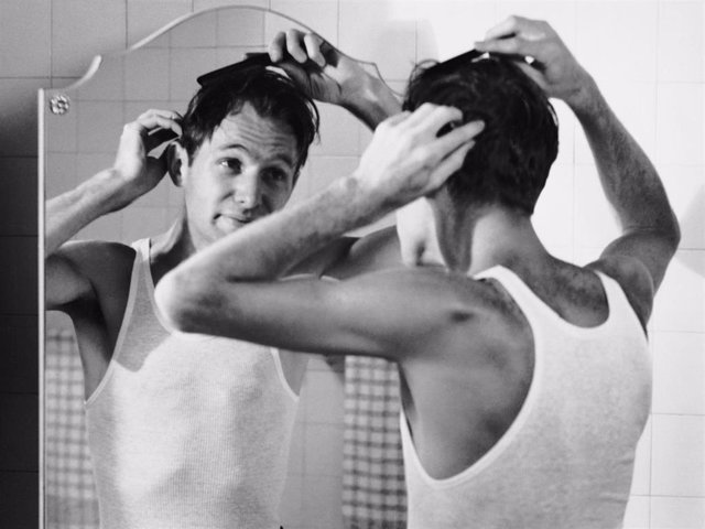 Man combing hair in bathroom