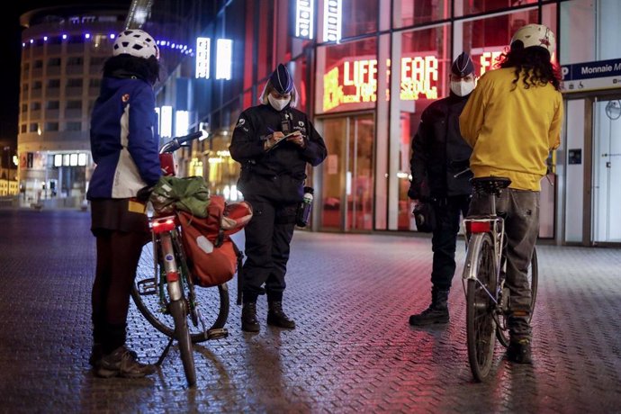 Policía belga habla con ciudadanos durante el toque de queda impuesto en Bélgica por la pandemia de coronavirus. 