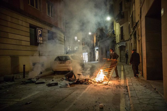30 October 2020, Spain, Barcelona: A man puts a barrier near burning trashes laid by protesters during a protest against the government's Coronavirus restrictions. Photo: Thiago Prudncio/SOPA Images via ZUMA Wire/dpa