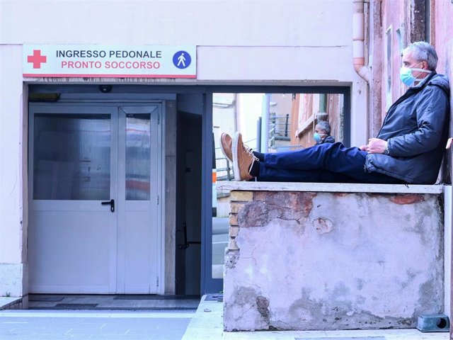 Un hombre con mascarilla espera a la puerta de un hospital en Roma durante la crisis del coronavirus