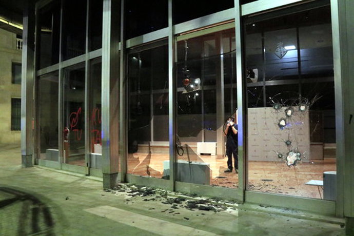 Un tcnic es mira els vidres trencats de l'Edifici Novíssim de l'Ajuntament de Barcelona, amb una pintada okupa, després d'una manifestació contra els desnonaments. 31 d'octubre del 2020. (Horitzontal)