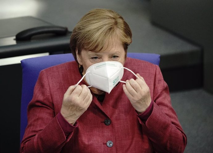 29 October 2020, Berlin: German Chancellor Angela Merkel removes her face mask as she arrives to attend a plenary session at the German Bundestag, where she will make a government declaration on how to cope with the coronavirus pandemic. Photo: Michael 