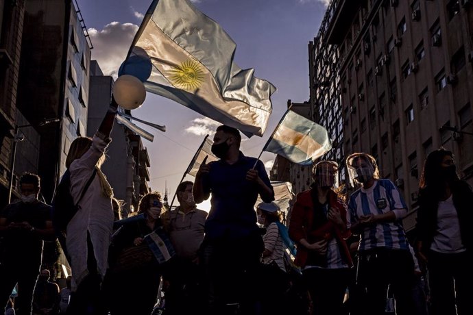 Manifestantes enarborlan banderas en una manifestación anti-cuarentena en Argentina. 