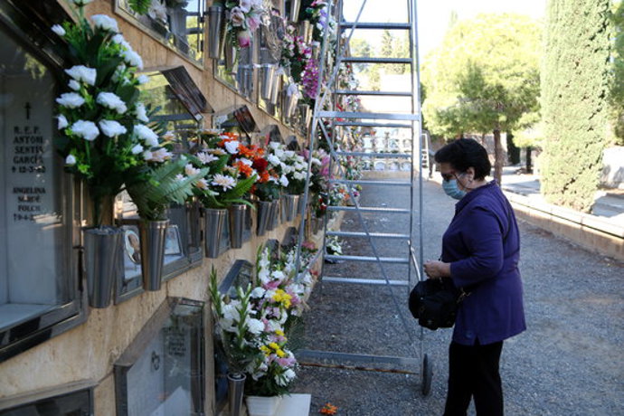 Pla general d'una dona portant les flors a una sepultura al cementiri de Tarragona en la festivitat de Tots Sants. Imatge de l'1 de novembre del 2020 (Horitzontal).