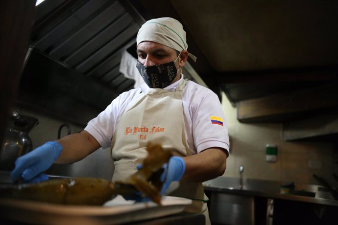 31 July 2020, Colombia, Bogota: A cook wraps a pie in a banana leaf at a restaurant as food services and snack bars are being allowed to resume operations gradually after three months of closure due to the coronavirus pandemic. Photo: Sergio Acero/colpr