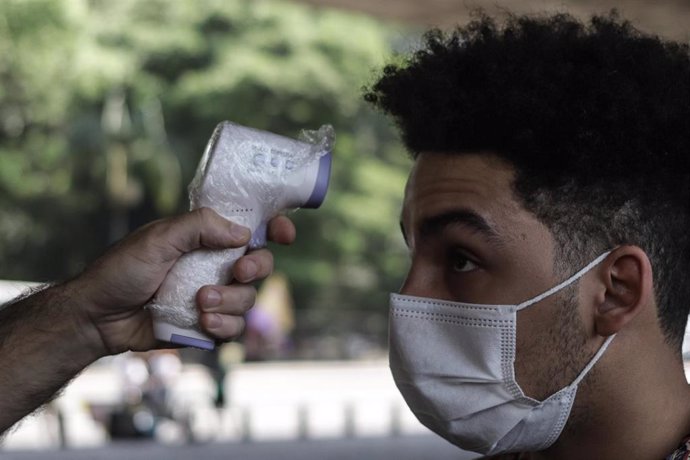 Un joven se somete una prueba de temperatura antes de ingresar en un espacio público de Sao Paulo, Brasil.