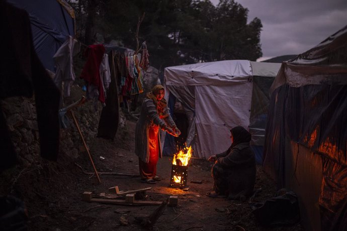 21 February 2020, Greece, Samos: Refugees warm themselves with a campfire in a refugee camp. The Greek government is building a new camp for refugees on the island of Samos. The camp will be able to accommodate 1,200 migrants. Photo: Angelos Tzortzinis/
