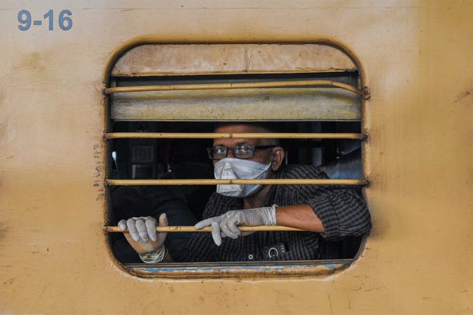 12 May 2020, India, Kolkata: Aman wearing a face mask and latex gloves looks through the window of a train. Indian railway network has resumed its operations partially as the country started to loose the Coronavirus measures. Photo: Debarchan Chatterje