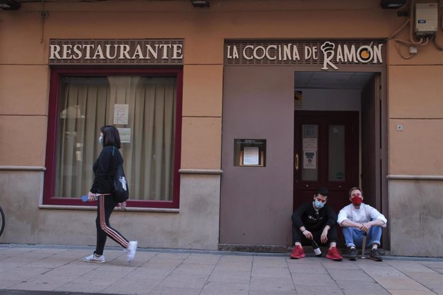 Ramón Piñeiro, propietario de 'La Cocina de Ramón' sentado junto a un empleado a la puerta del local  a 30 de octubre de 2020.