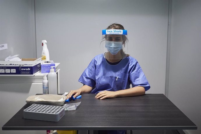 Una trabajadora sanitaria sentada en su puesto donde acuden pacientes a extraerse muestras.