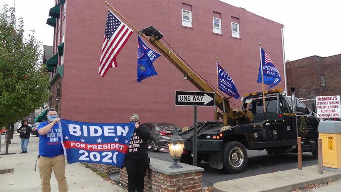 Partidarios de Joe Biden muestran un cartel a su favor junto a banderas a favor de Donald Trump en Pensilvania