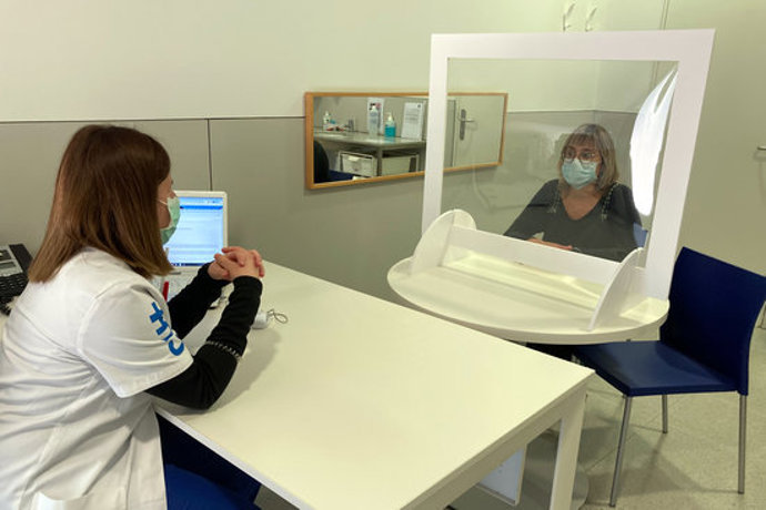Pla general de la consulta d'una logopeda atenent una docent com a usuria darrere d'una pantalla de protecció el 3 de novembre del 2020 a Manresa. (horitzontal)