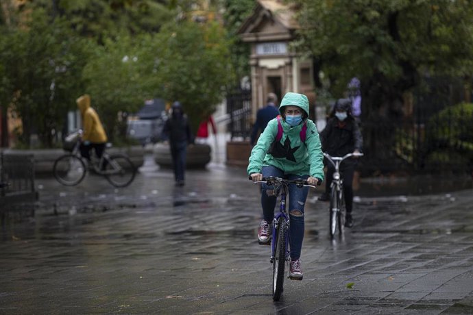 Varias personas circulan en bicicleta durante una jornada de lluvia. En Sevilla (Andalucía, España), a 22 de octubre de 2020.