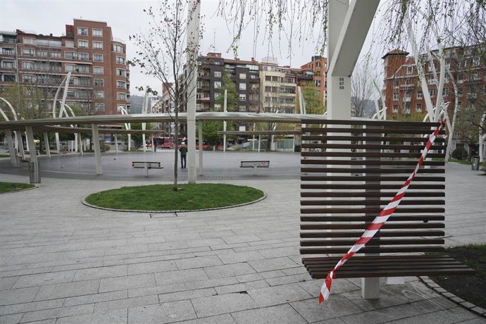Un banco precintado en una calle de Bilbao que despierta totalmente vacía en la tercera semana de cuarentena