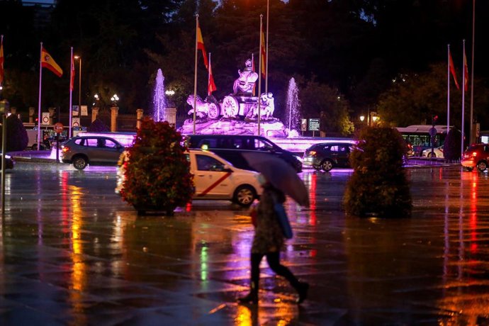 Una persona pasea bajo un paraguas por la Plaza de Cibeles un día marcado por una bajada de temperaturas y lluvias, en Madrid (España), a 20 de octubre de 2020. Una treintena de provincias estarán este martes 20 de octubre en riesgo naranja (importante)