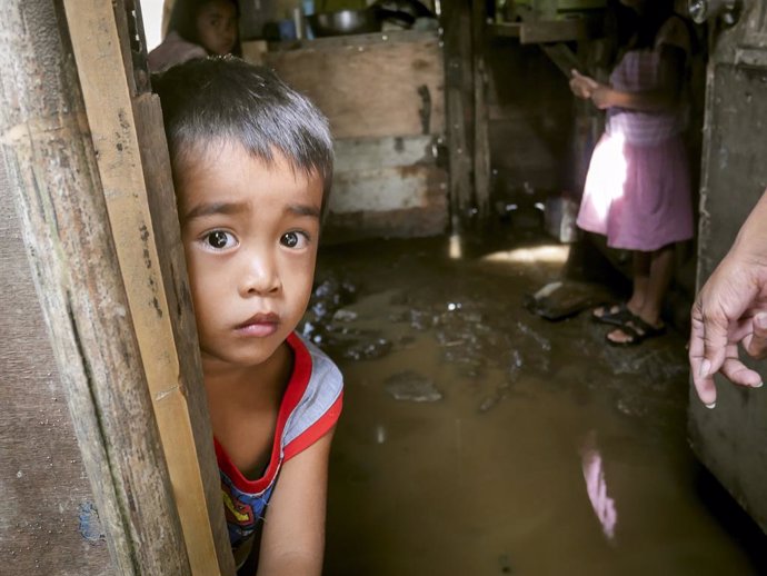 Un niño en una casa inundada por el paso del tifón 'Goni' en Batangas (Filipinas)