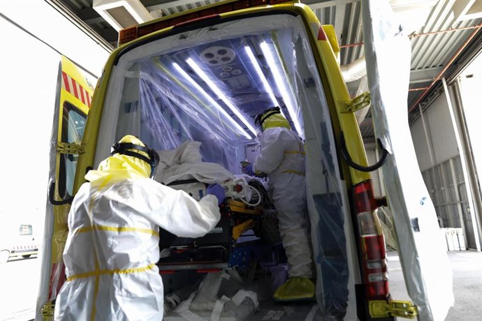 Sanitarios protegidos con un traje protector frente al Covid-19 trasladan a un paciente, foto de archivo