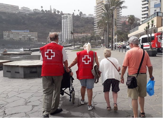 Un cuidador y dos personas mayores a su cargo dan un paseo en Puerto de la Cruz, acompañados por dos voluntarios del proyecto de Cruz Roja