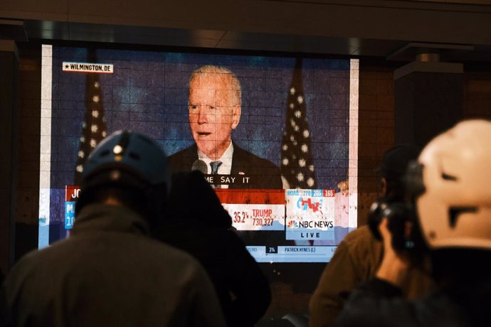 Un grupo de personas observa el discurso de Joe Biden en Washington la noche electoral