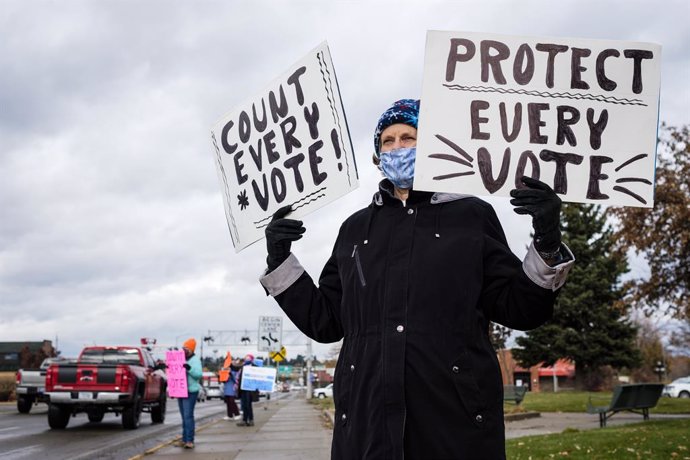 04 November 2020, US, Kalispell: An activist holds signs during a rally at Depot Park to demand that every vote be counted in the still contested USPresidential election. Photo: Kent Meireis/ZUMA Wire/dpa