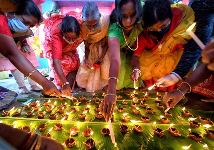 24 October 2020, India, Kolkata: Hindu devotees wear face masks as they light oil lamps, also known as Diyas, in front of Lord Durga idol during the Sandhi Puja Ritual of the Durga Ashtami festival. Photo: Avishek Das/SOPA Images via ZUMA Wire/dpa