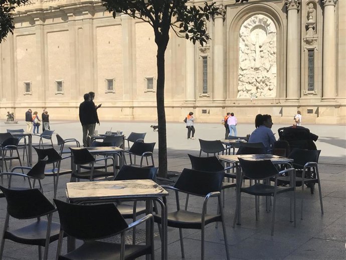 Terraza con mesas y sillas y el Pilar de fondo