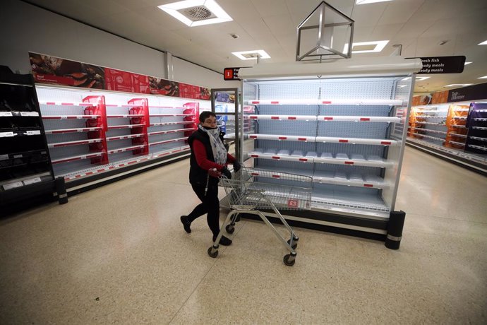 19 March 2020, England, Telford: A woman shops as empty shelves are seen at a Sainsbury, amid a wave of panic buying because of fears of the spread of Coronavirus (SARS-CoV-2). Photo: Nick Potts/PA Wire/dpa
