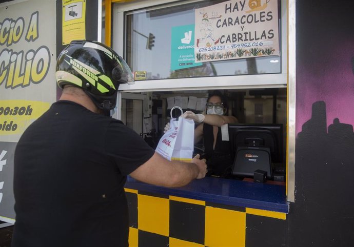 Una persona recoge un pedido de comida para llevar en un bar. 