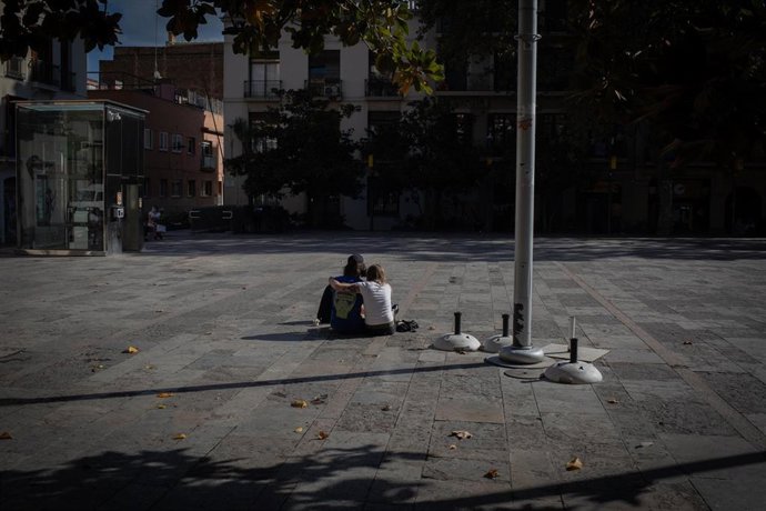 Una pareja sentada en la Plaza de la Virreina, en Barcelona, Catalunya(España) a 23 de octubre de 2020.