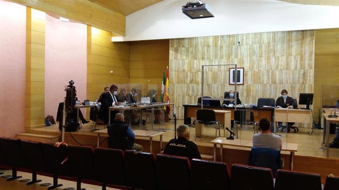 Juicio al supuesto autor del asesinato y enterramiento de su mujer en Guadix, de espaldas, el primero a la izquierda del policía en la imagen