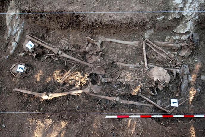 Pla mitj picat de la fossa comuna prop de Pamplona amb tres esquelets (horitzontal).
