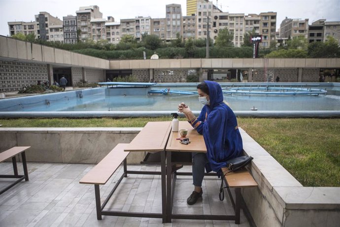 Una mujer con mascarilla en una cafetería de Teherán