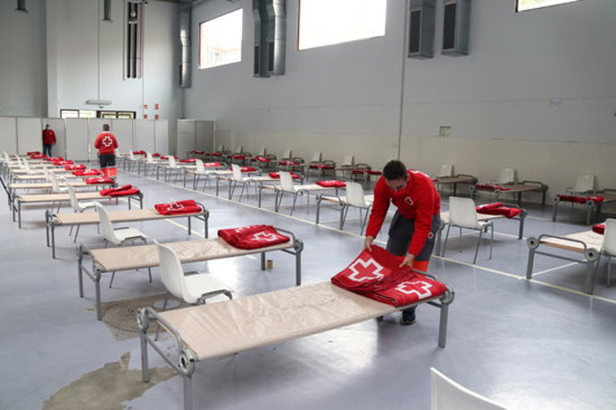 Pla general d'un tcnic de Creu Roja habilitant un llit de l'alberg per a sensesostres del Palau Firal de Tarragona. Foto del 6 de novembre del 2020 (horitzontal).