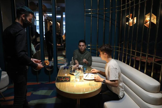 Un camarero sirve a dos comensales de una mesa del Restaurante Marta, Cariño!, en Madrid (España), a 16 de octubre de 2020. 
