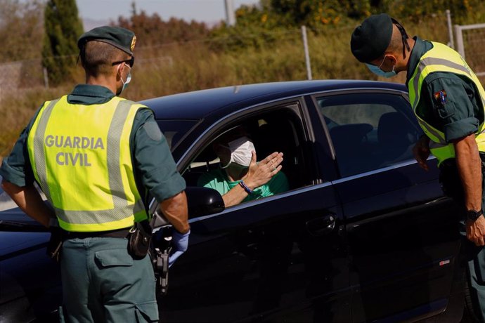 Dos guardias civiles junto a un conductor parado en un dispositivo para controlar el cumplimiento de las medidas sanitarias
